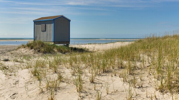 A beach hut with a simple structure, situated on a sandy dune with grass in the foreground. - Brigantine Condo w/ Beach Access & Pool Views (Brigantine)