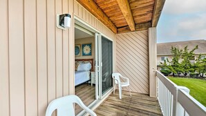 A balcony with a wooden floor, white railing, and a white plastic chair. - Brigantine Condo w/ Beach Access & Pool Views (Brigantine)