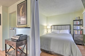 A bedroom with a bed, bedside table, lamp, and bookshelf. - Cali Studio w/ Resort Perks: 6 Mi to San Fran (Daly City)