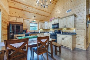 A wooden cabin kitchen with a dining area, including a refrigerator, microwave, stove, and wooden cabinets. - 'penny Lane Lodge' Broken Bow Cabin < 6 Mi to Lake (Broken Bow)