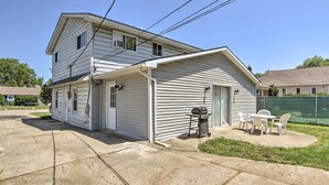 Ein zweistöckiges Haus mit überdachter Veranda, Grill und Sitzgelegenheit im Freien.