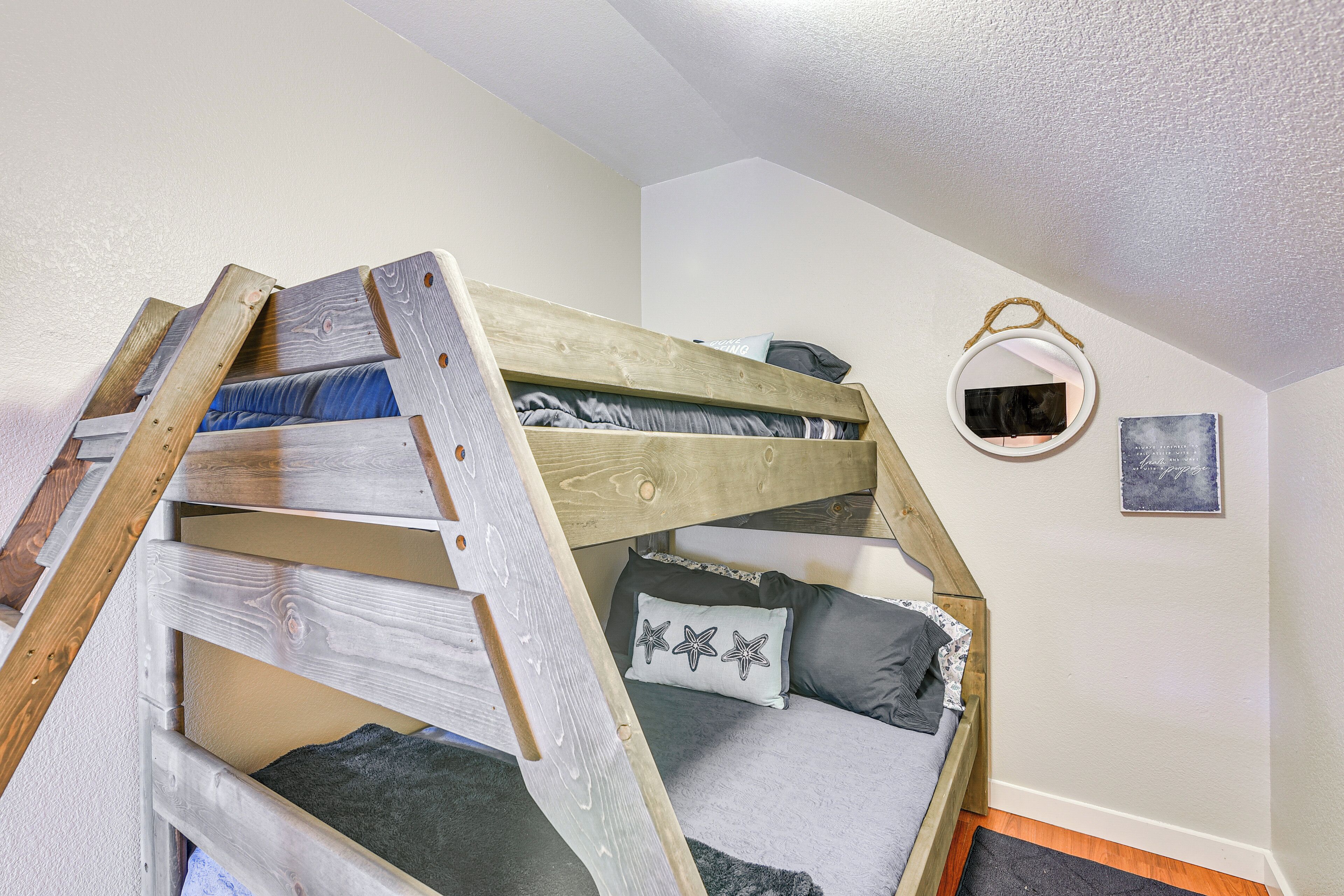 A bunk bed with a wooden ladder, a small mirror, and a pillow with star patterns.