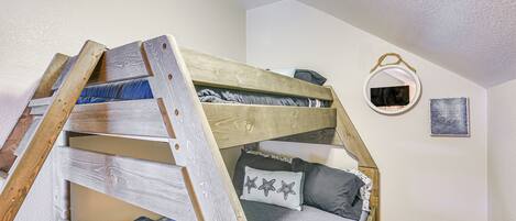 A bunk bed with a wooden ladder, a small mirror, and a pillow with star patterns.