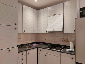 A kitchen with white cabinets, a black countertop, and a gas stove.
