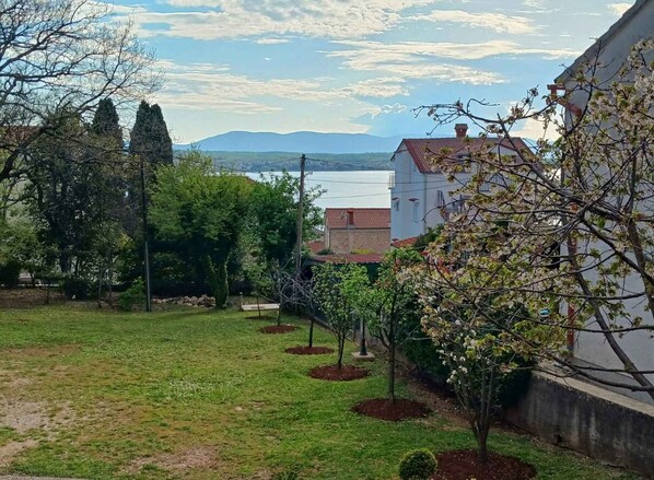 Un barrio residencial con jardín, árboles y un edificio de techo rojo.