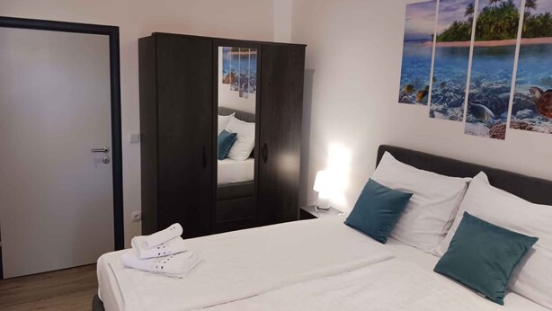 Ein Hotelzimmer mit einem Bett, einem Kleiderschrank und einer Wand mit einem tropischen Wandbild.