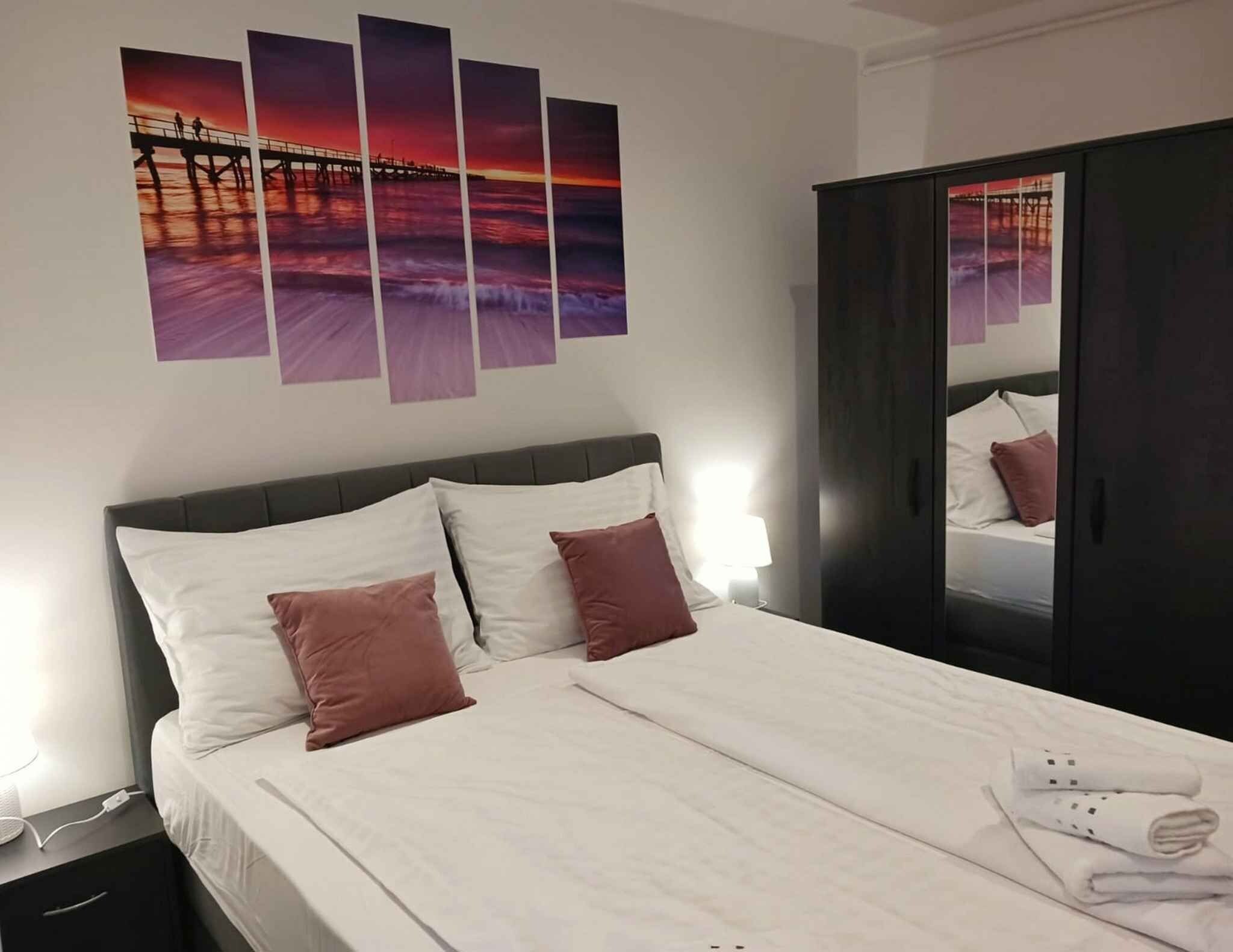 Ein Hotelzimmer mit einem Bett, Kissen, einem Nachttisch, einer Lampe und einem Kleiderschrank.