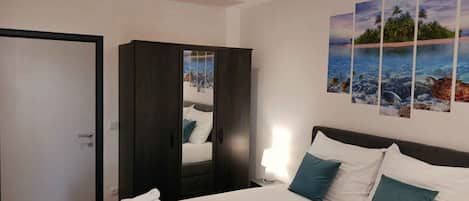Habitación de hotel con cama, armario, puerta y pared decorada con un mural tropical.