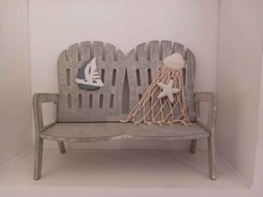 A wooden bench with a nautical-themed backrest, featuring a sailboat and a starfish.