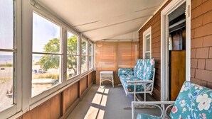 A covered porch with a wooden floor, a white table, and two floral-patterned chairs.