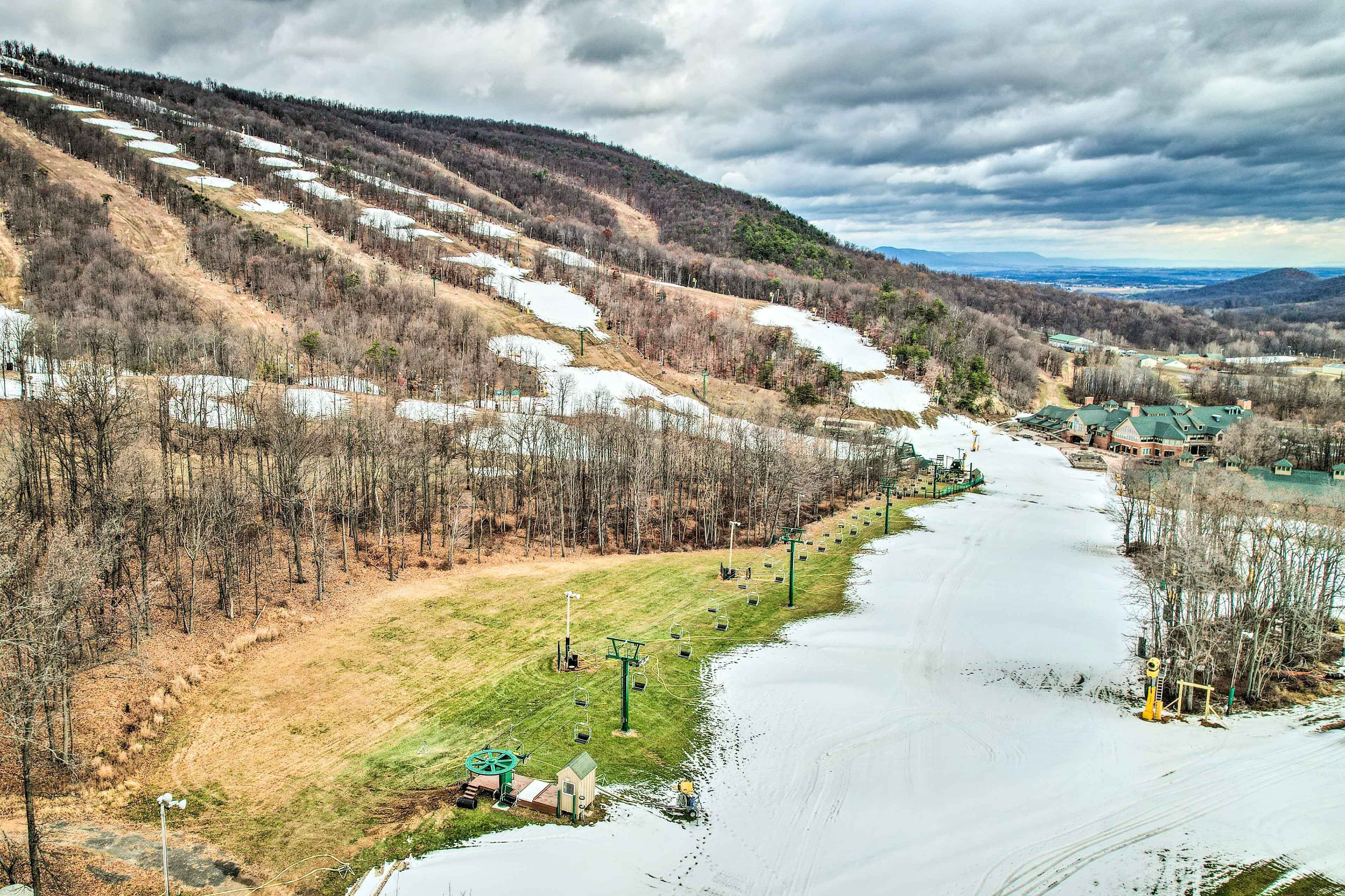 A ski resort with a chairlift, a river, and buildings in the background.