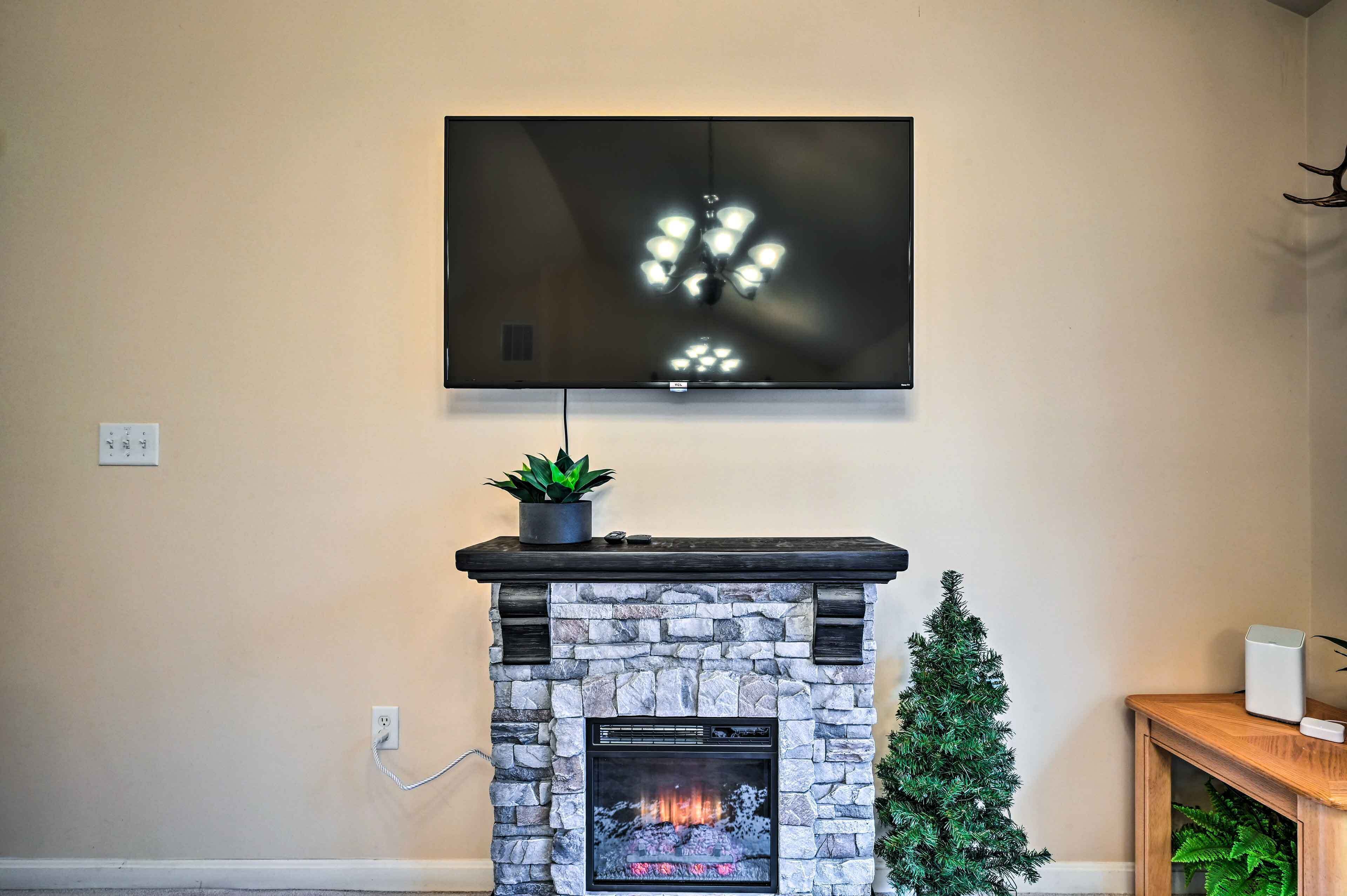 A stone fireplace with a TV mounted above it, a small Christmas tree, and a plant on the mantel.