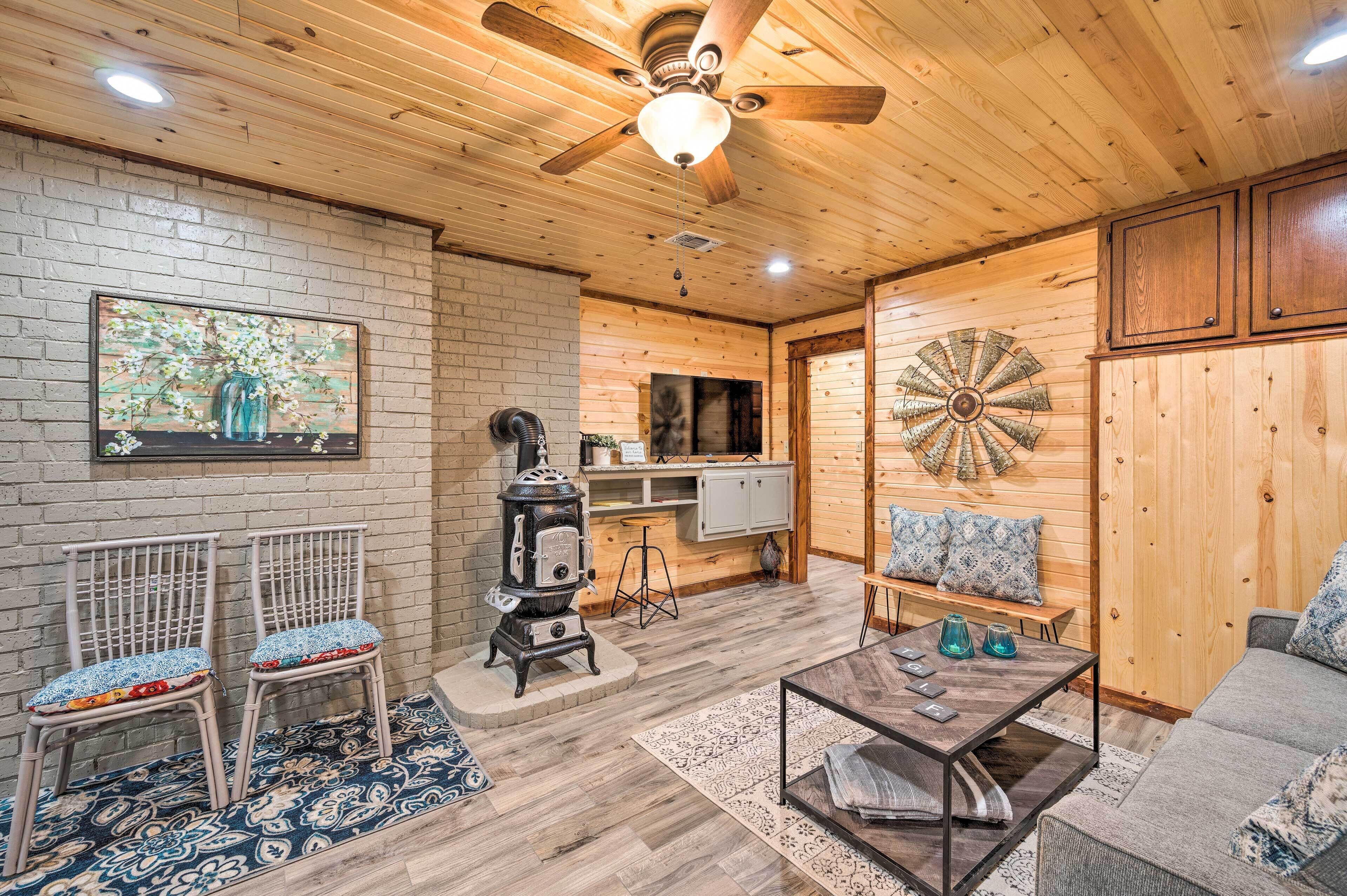 A cozy room with a wooden ceiling, a ceiling fan, a fireplace, a dining table, and a sofa.