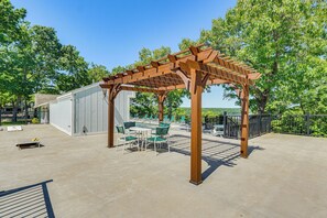 An outdoor patio with a wooden pergola, a dining table with chairs, and a covered seating area. - 1 Mi to Margaritaville Resort! Getaway w/ Hot Tub (Osage Beach)
