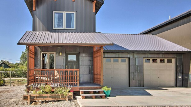 A two-story building with a wooden porch and a garage. - Pet-friendly Choteau Townhouse With Gas Grill! (Choteau)