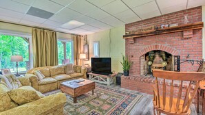 A cozy living room with a brick fireplace, comfortable seating, and a television. - Chauga River Cabin: Pets Welcome! (Mountain Rest)