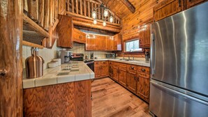 Una cocina rústica con armarios de madera, un refrigerador de acero inoxidable y una araña.
