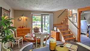 A spacious living area with a dining table, chairs, a wooden staircase, and a view of the outdoors. - Lakeview A-frame Steps to Marina & Old Field Beach (Lakeview)