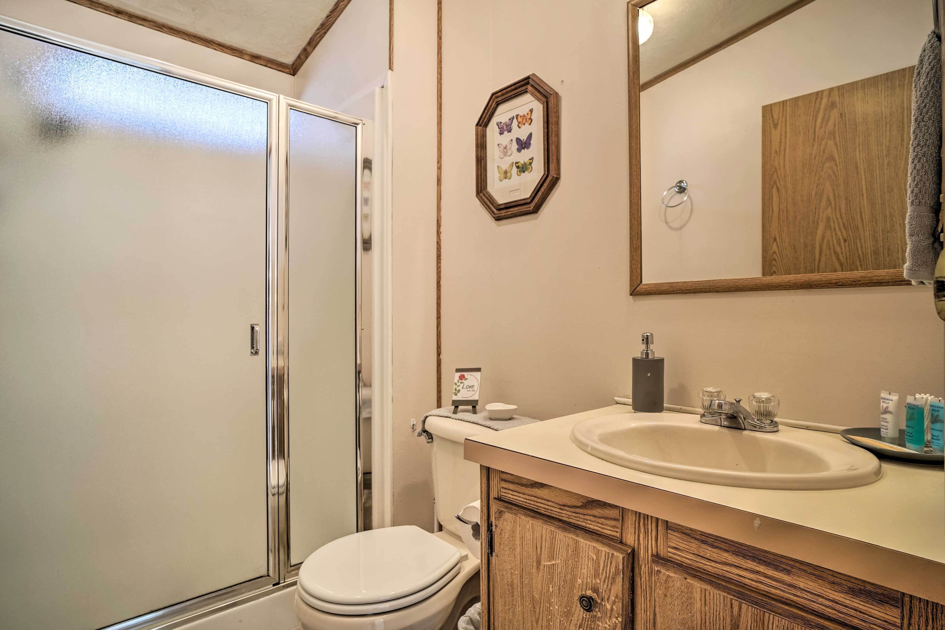 A bathroom with a toilet, sink, mirror, and shower.