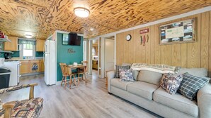 Ein gemütliches Interieur mit Holzbalkendecke, einer Küchenzeile, einem Essbereich und einer Couch mit gemusterten Kissen.
