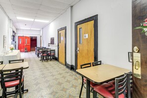 A hallway with tables and chairs, doors, and a tiled floor. - Direct Trail Access! ATV Riding Home Base in Gary (Gary)