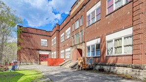 A red brick building with multiple windows, a red door, and a staircase leading to an upper level. - Direct Trail Access! ATV Riding Home Base in Gary (Gary)