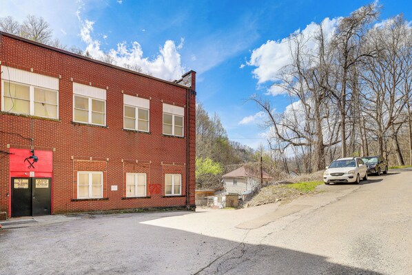 A red brick building with a garage door, a small attached structure, and a paved driveway.