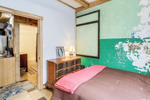 A bedroom with a bed, dresser, and a green wall with peeling paint. - Direct Trail Access! ATV Riding Home Base in Gary (Gary)