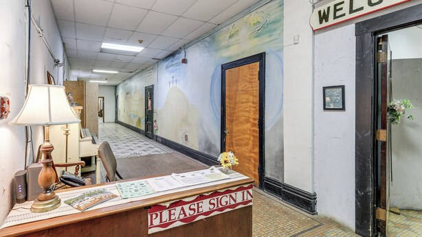 A reception desk with a 'Please Sign In' sign, a lamp, a chair, and a wall mural. - Direct Trail Access! ATV Riding Home Base in Gary (Gary)