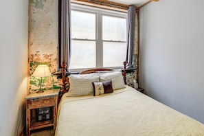 A bedroom with a bed, a nightstand, a lamp, and a window with curtains. - Direct Trail Access! ATV Riding Home Base in Gary (Gary)