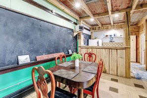 A wooden dining area with a blackboard, a plant, and a kitchen counter with a sign.