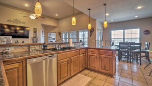 A modern kitchen with wooden cabinets, a dishwasher, and pendant lighting.