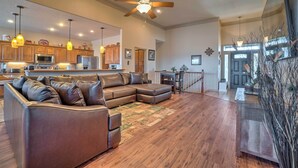 A spacious living room with a sectional sofa, wooden flooring, and a ceiling fan.