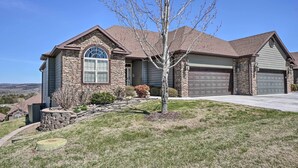 A two-story house with a stone facade, a garage, and a well-maintained lawn.