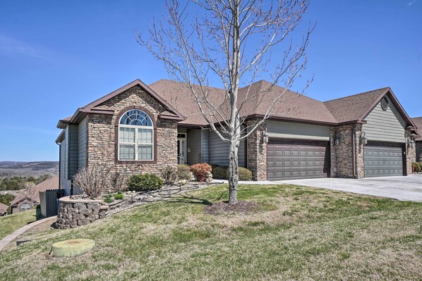 A two-story house with a stone facade, a garage, and a well-maintained lawn.