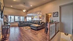 A spacious living room with a large sectional sofa, wooden flooring, and a staircase with a railing.