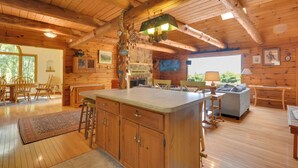 Interno di una baita in legno con cucina, zona pranzo e soggiorno.