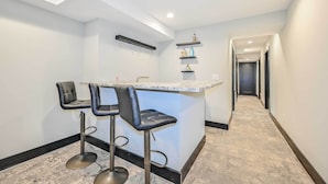 A modern kitchen with a bar area, marble countertops, and a hallway leading to other rooms. - 5 Mi to Mercedes-benz Stadium: Stylish ATL Retreat (Atlanta)