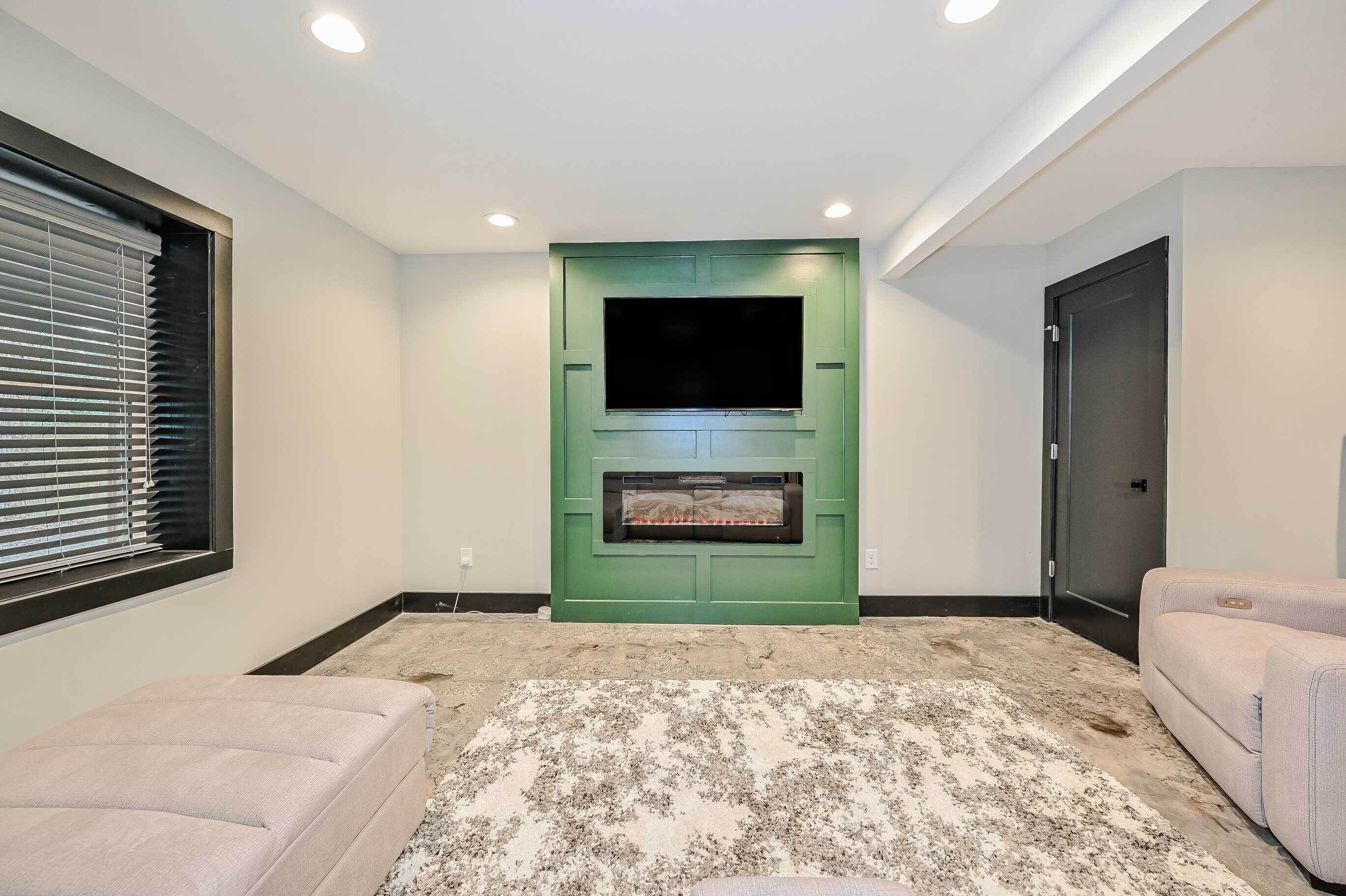A living room with a green entertainment unit, a fireplace, and two sofas.
