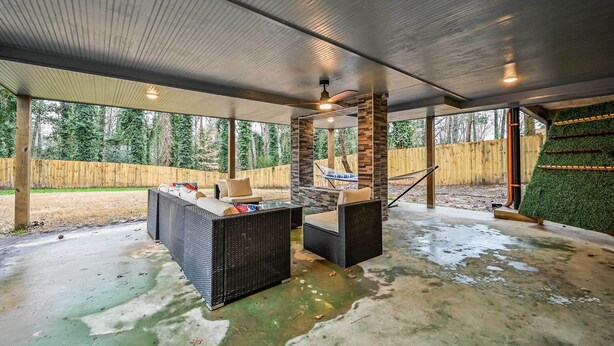 An outdoor patio with a stone fireplace, wicker furniture, and a view of a wooded area. - 5 Mi to Mercedes-benz Stadium: Stylish ATL Retreat (Atlanta)