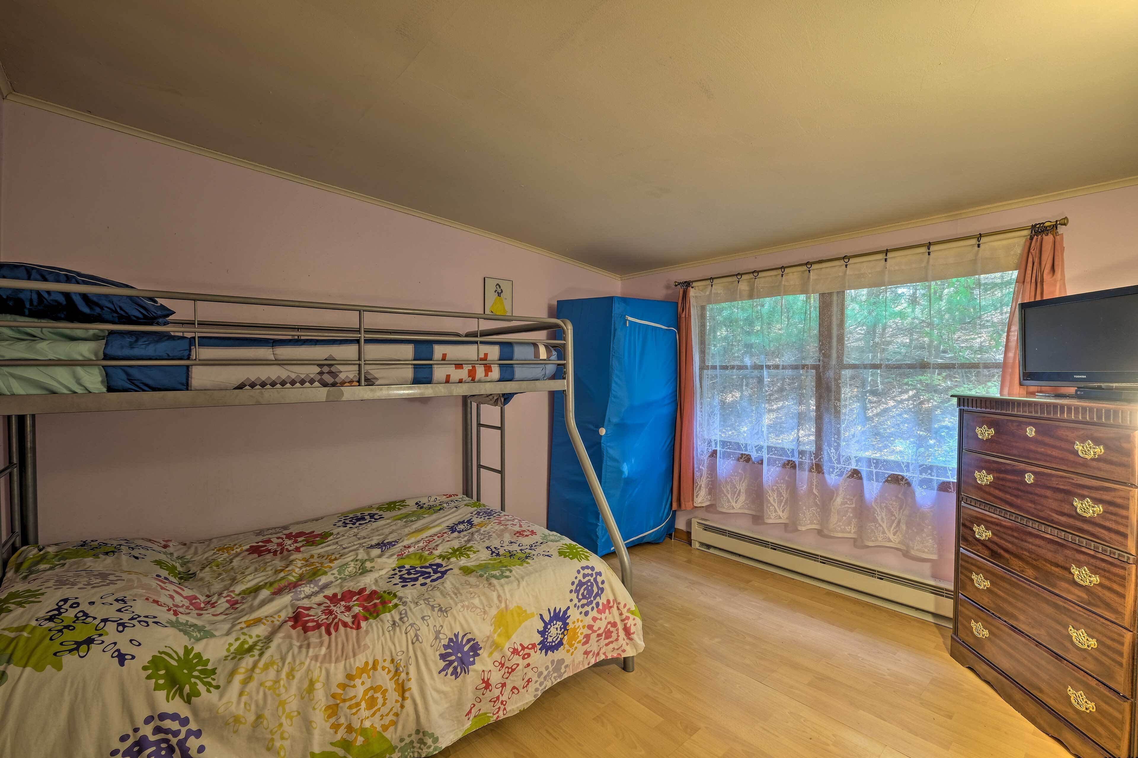 A room with bunk beds, a dresser, and a window with curtains.