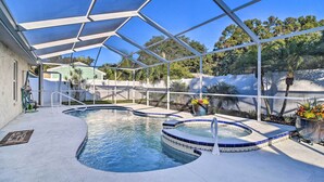 Une piscine dotée d’une structure servant de parasol, d’un jacuzzi et d’une petite cascade décorative.