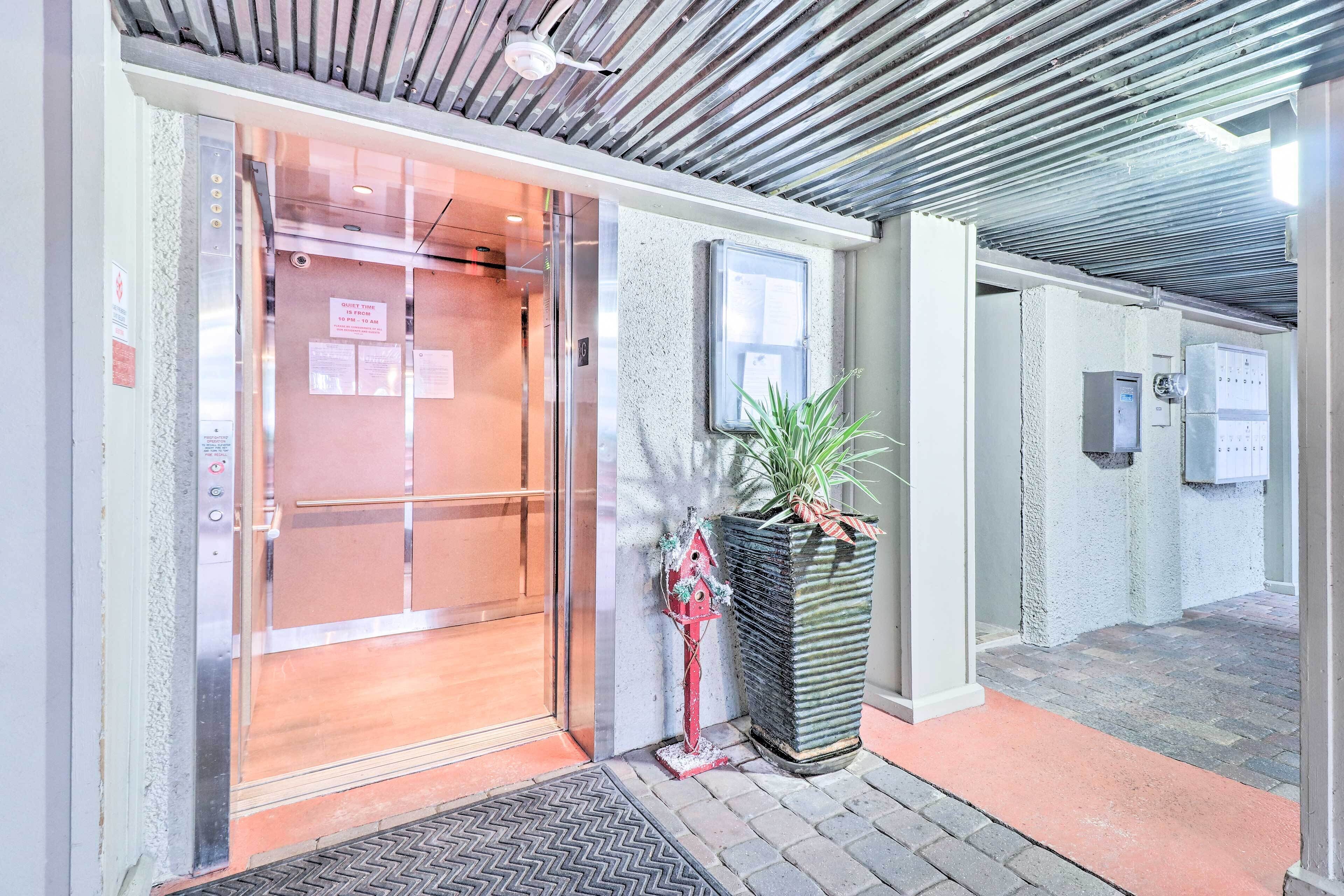 Elevador com porta de vidro, um vaso de planta e painel de controle fixado na parede.