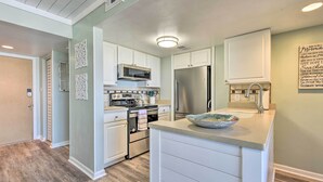 Une cuisine moderne avec des meubles blancs, des appareils en acier inoxydable et un plancher en bois.