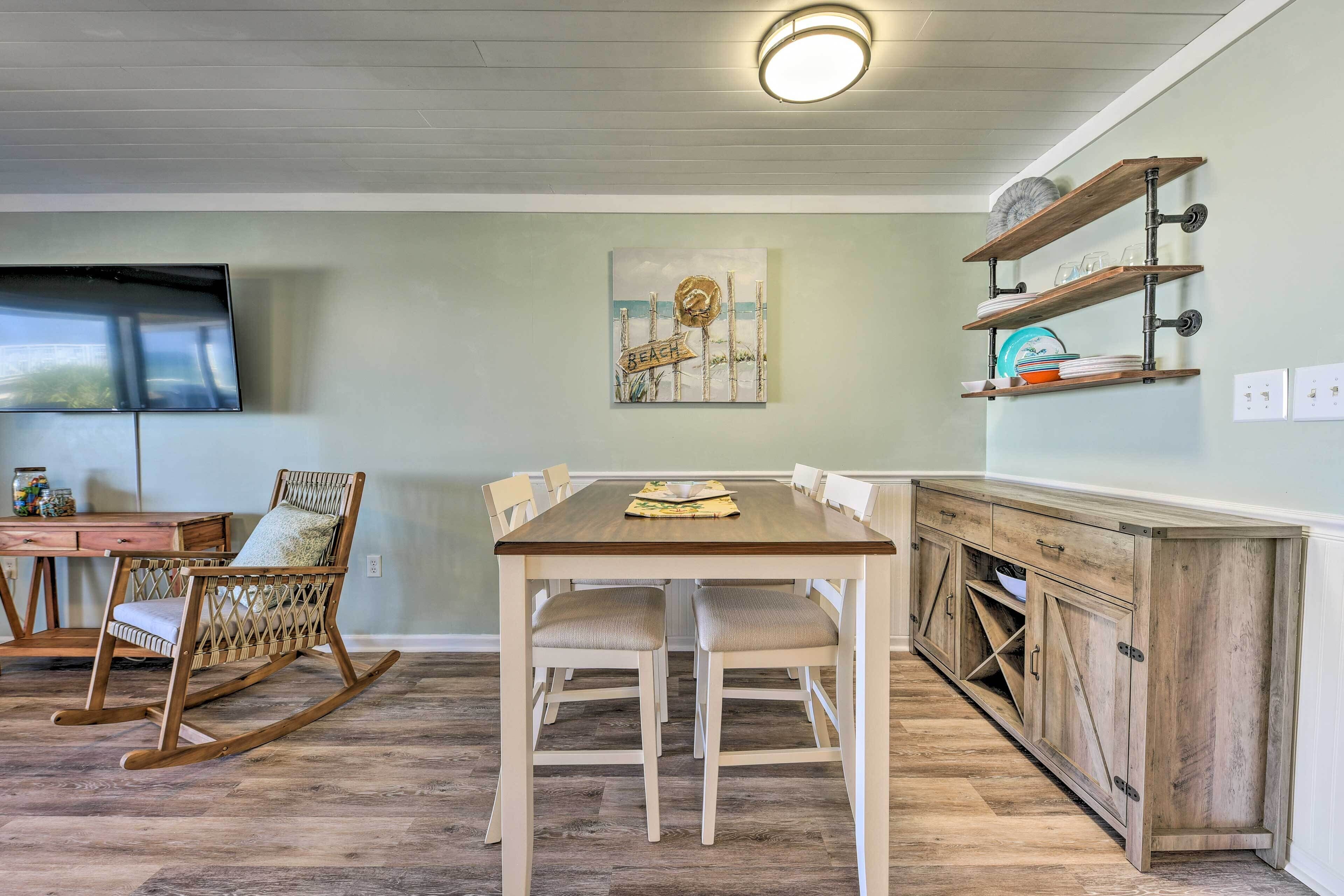 Un coin repas avec une table et des chaises en bois, un fauteuil à bascule, un tableau accroché au mur et une étagère intégrée où sont rangées de la vaisselle.