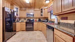 Una cocina con armarios de madera, un refrigerador de acero inoxidable, un microondas, un horno y un lavavajillas.