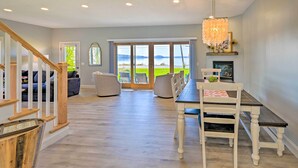 A spacious living area with a dining table, chairs, and a view of a lake through large sliding glass doors. - Charming Saratoga Lake Retreat w/ Dock Access (Saratoga Springs)