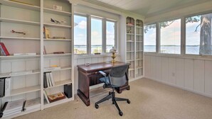 Ein Zimmer mit Schreibtisch, Stuhl und Bücherregalen.