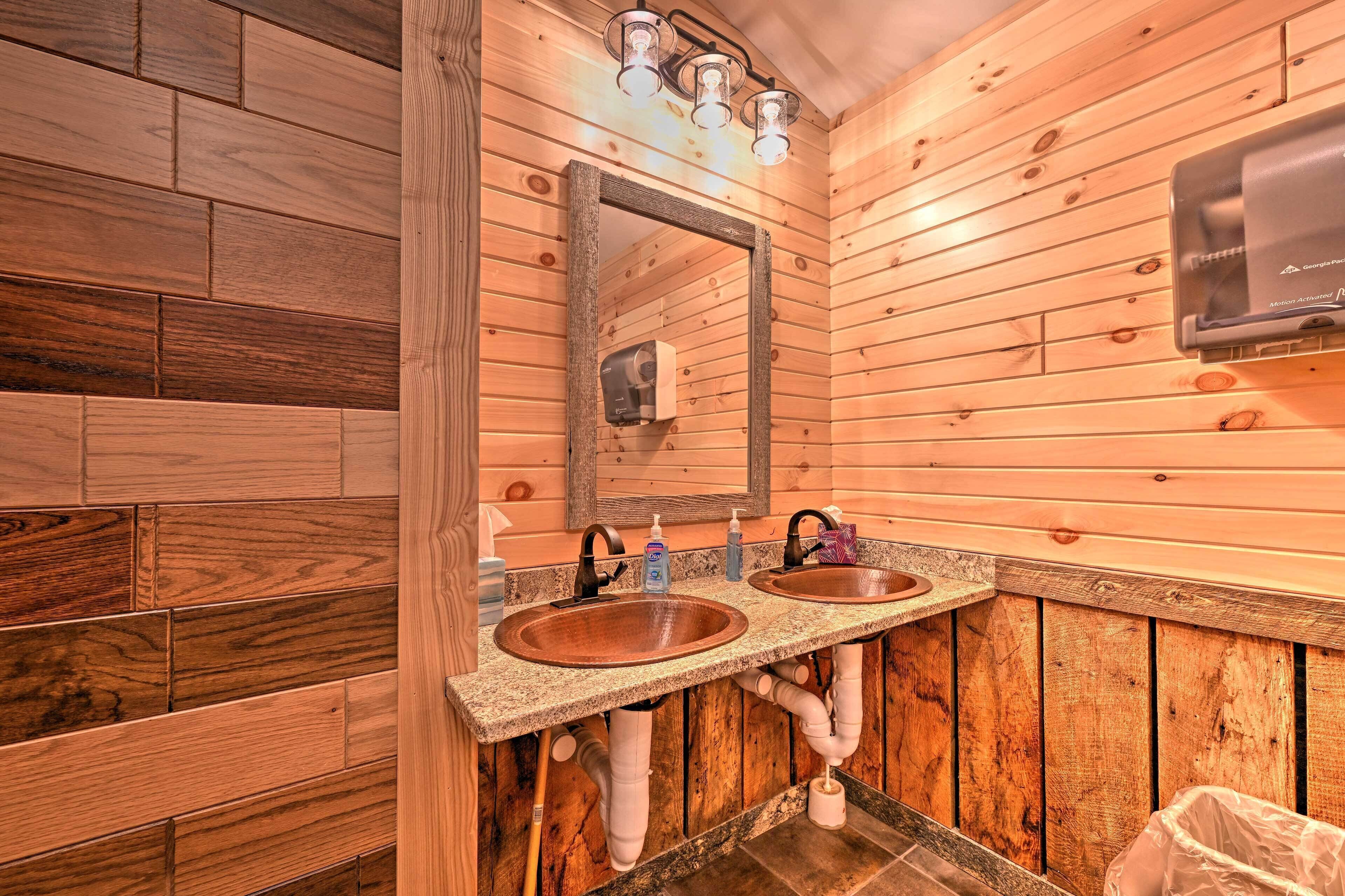 A wooden-paneled bathroom with two sinks, a mirror, and a soap dispenser.