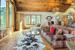 Ein rustikales Interieur mit Holzbalken, einem Ledersofa, einem Glastisch und einem Kuhfellteppich.